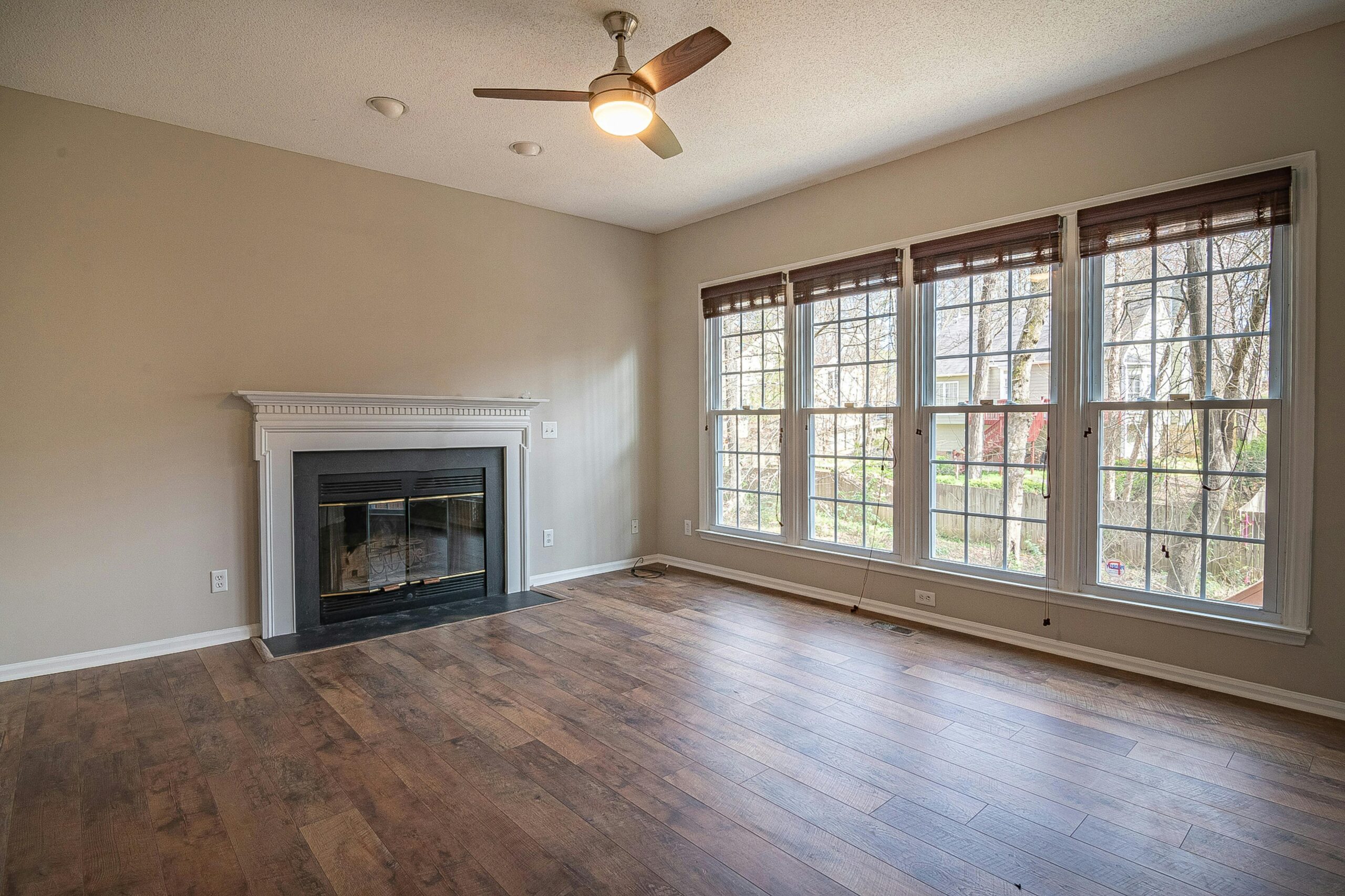 A bright and spacious modern living room interior with a fireplace and large windows.